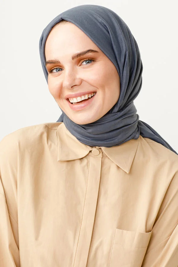 Smiling woman wearing the slate blue Comfort Cotton Hijab with a beige shirt
