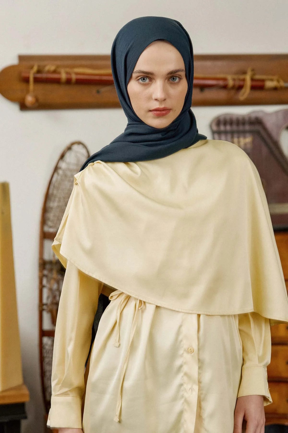 Woman wearing the petrol Comfort Cotton Hijab with a cream outfit, front view