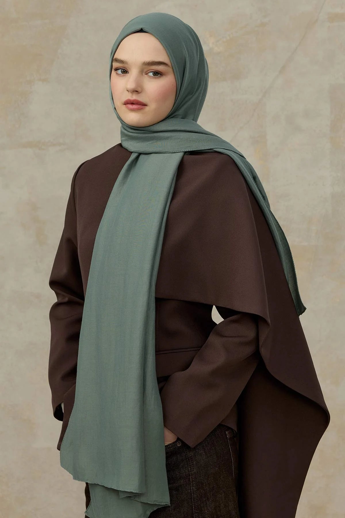 Woman wearing the dusty teal Comfort Cotton Hijab with a chocolate brown wrap coat