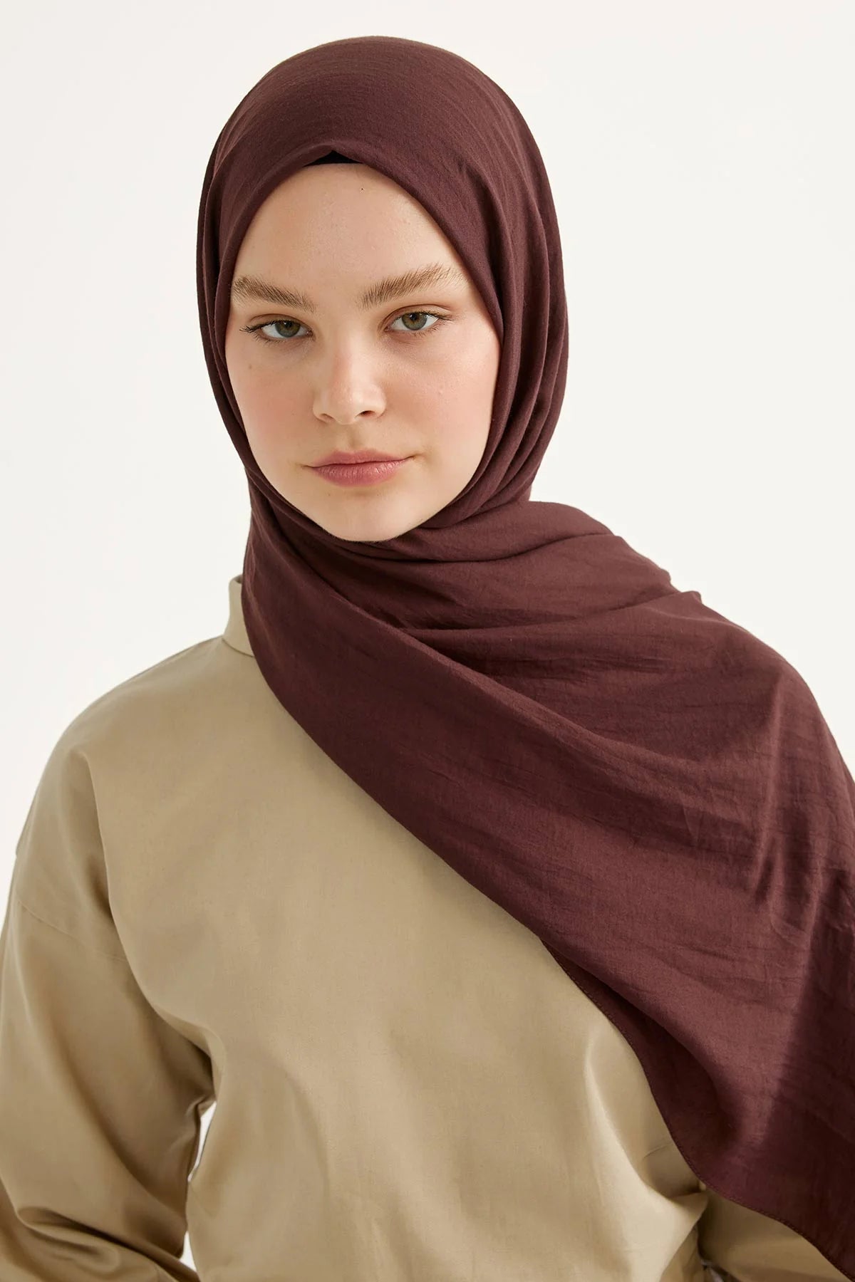 Woman wearing the plum Comfort Cotton Hijab with a beige top, front view