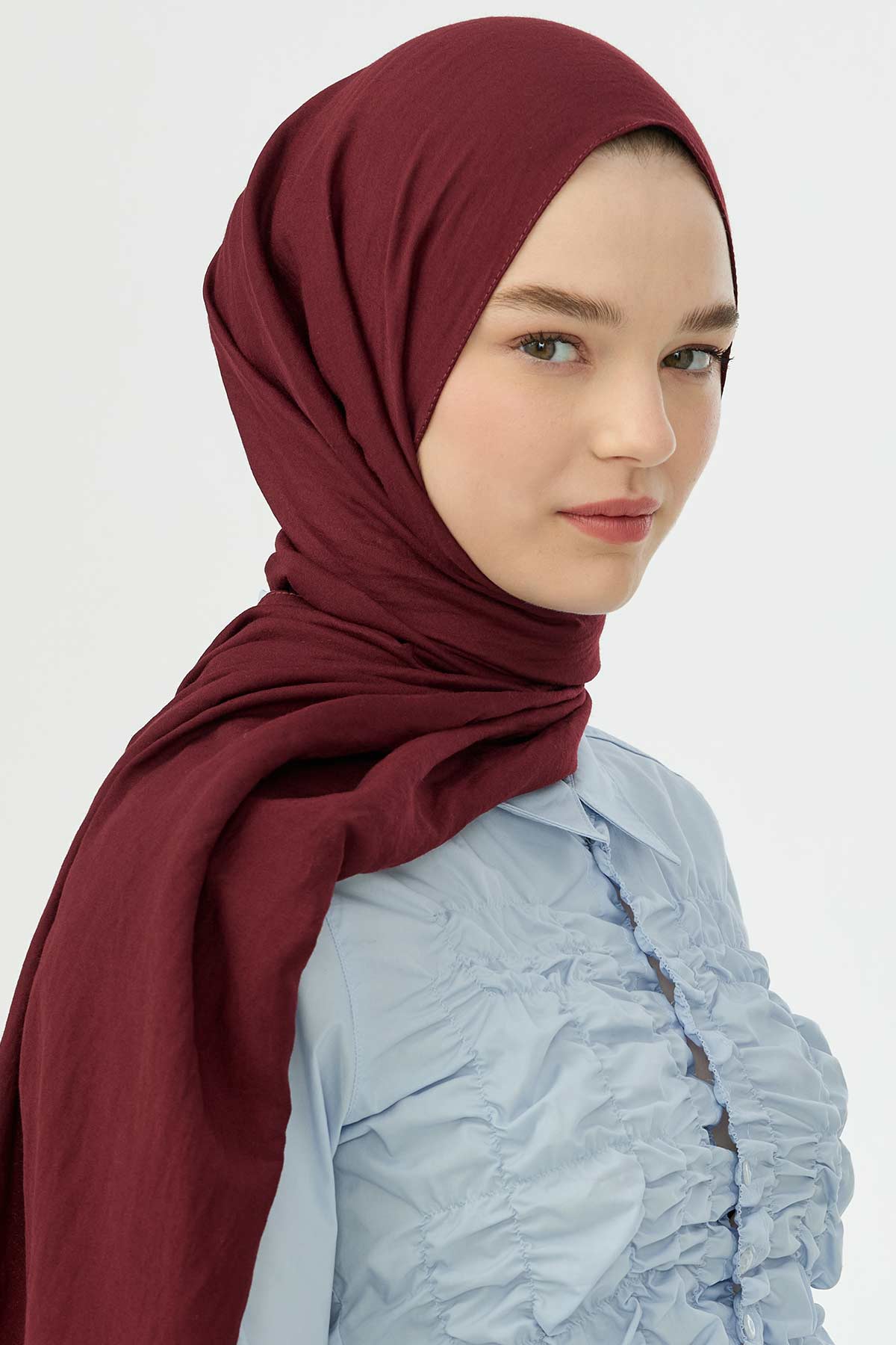Woman wearing the maroon Comfort Cotton Hijab with a pale blue blouse, front view
