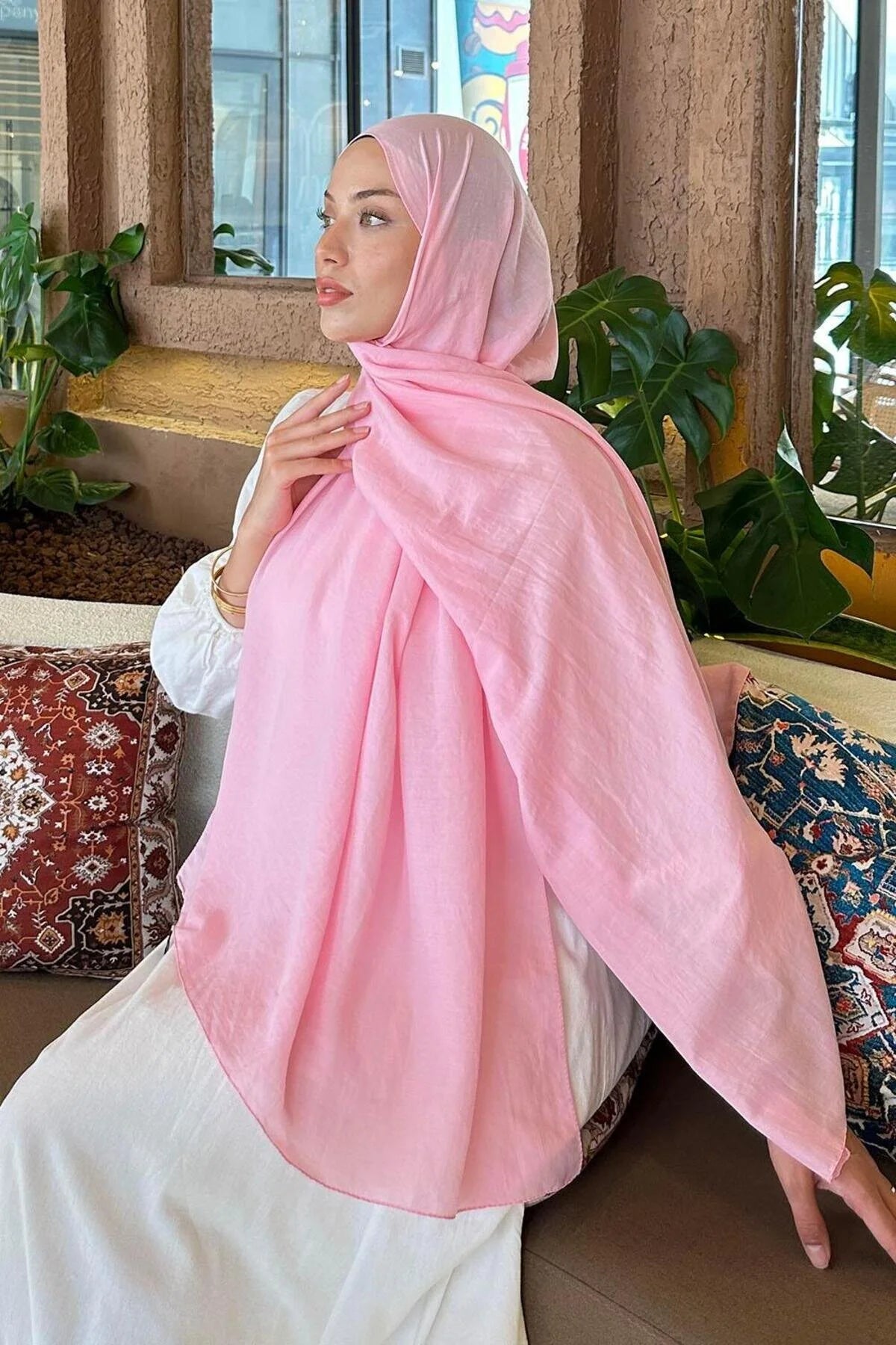 Model adjusting the pink Comfort Cotton Hijab, showing the soft drape