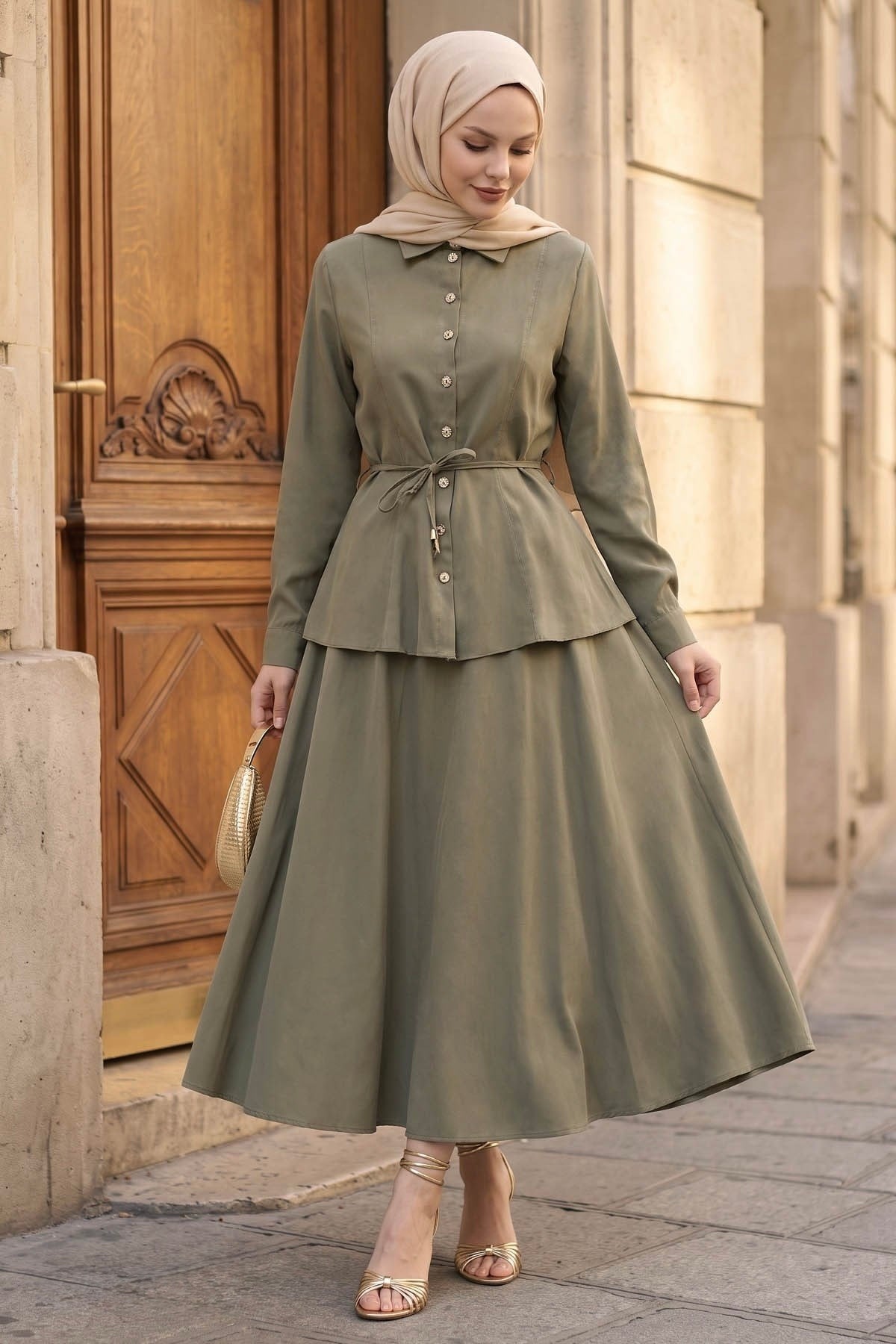 Woman in a hijab wearing the Ayla modest skirt set in sage: tie-waist button-front shirt and A-line maxi skirt, front view
