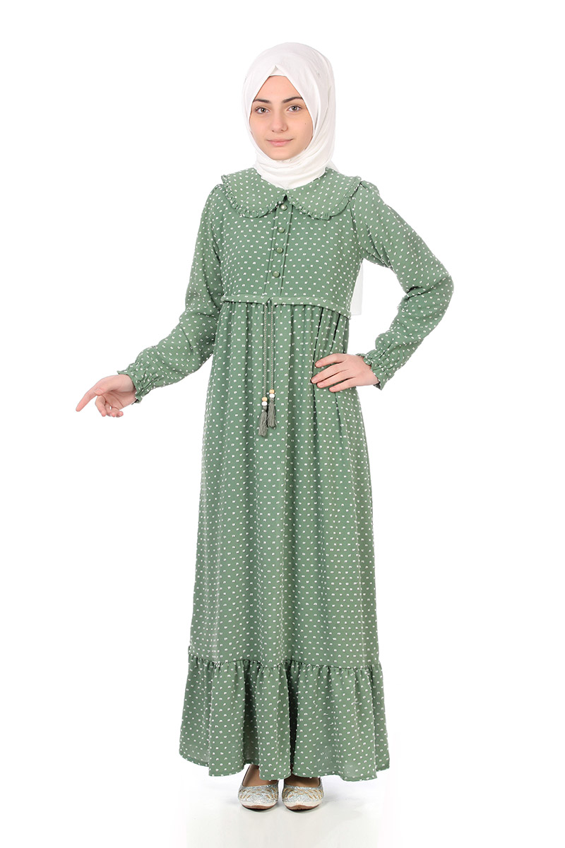Model in a white hijab wearing the Zara girls' modest maxi dress in teal polka dot with tassel tie waist