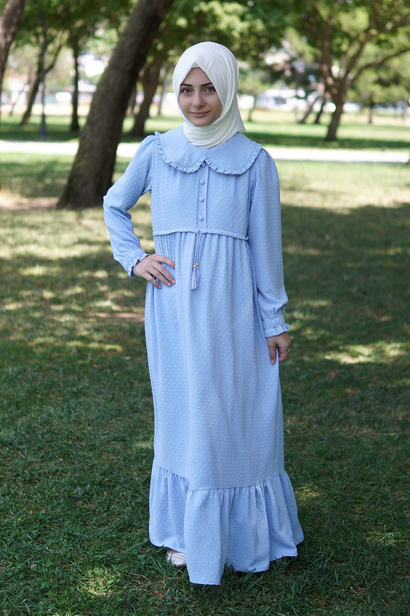 Model in a white hijab wearing the Zara girls' modest maxi dress in light blue polka dot with Peter Pan collar, outdoors
