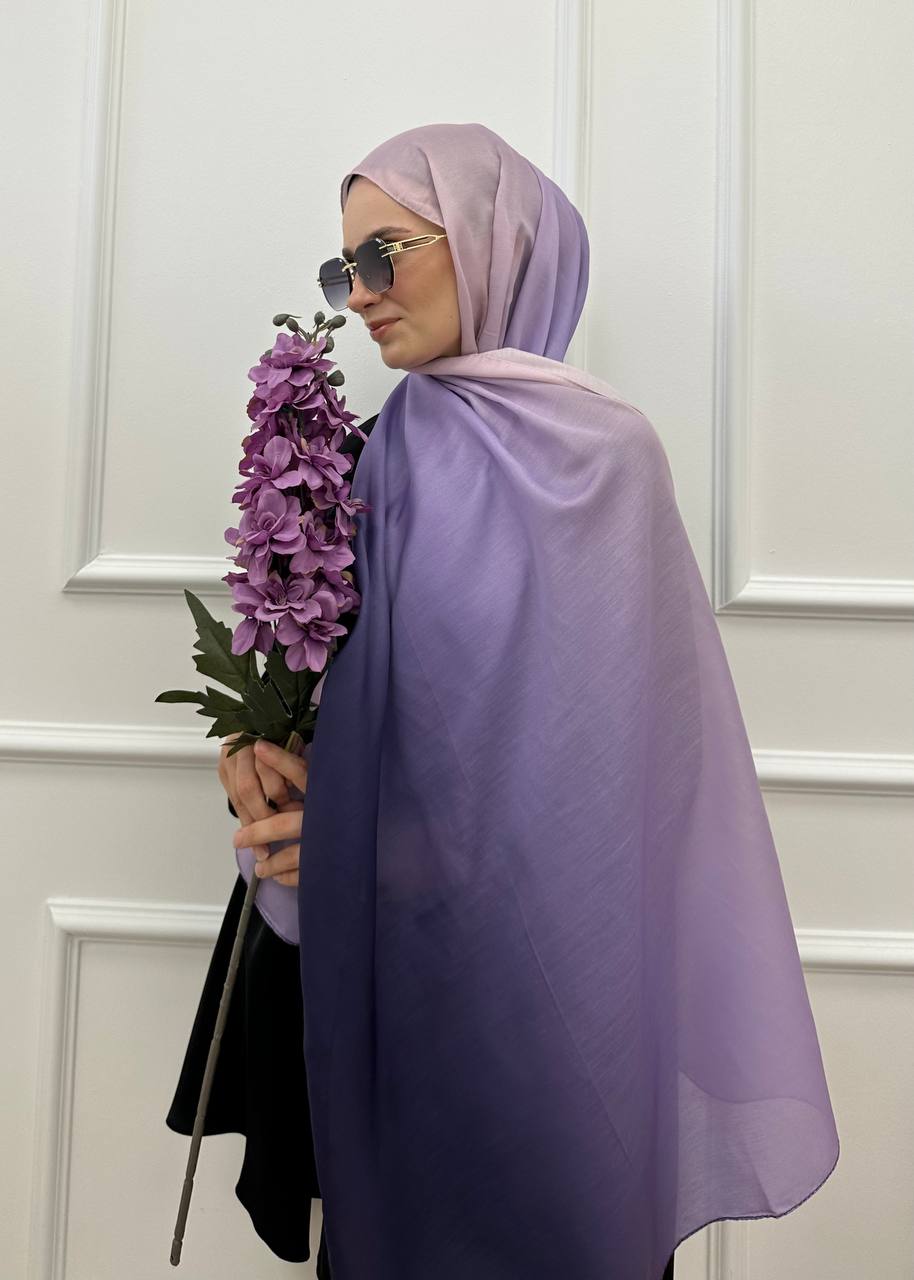 MODESTIQUE Ombre Hijab in lavender, worn with sunglasses and holding purple flowers, side view.