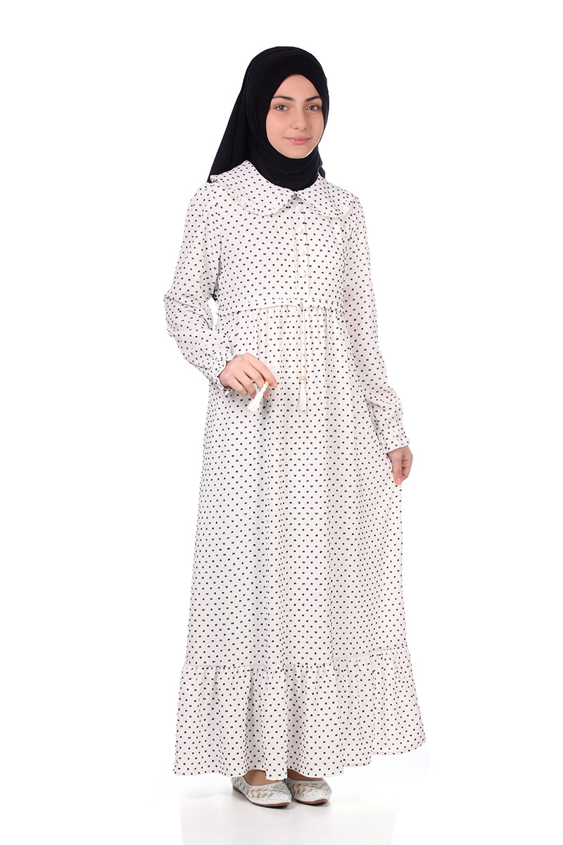 Model in a black hijab wearing the Zara girls' modest maxi dress in white polka dot with Peter Pan collar and ruffle hem