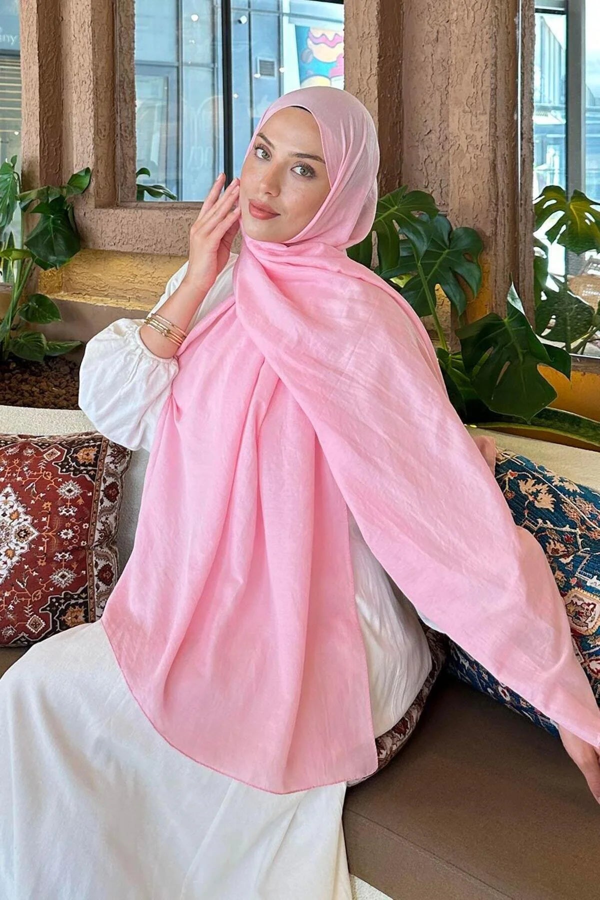 Woman in a pink Comfort Cotton Hijab draped over a white dress, seated view