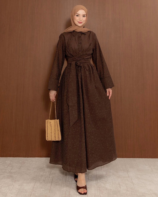 Full-length front view of the MODESTIQUE Fleur Wrap Dress in Brown, tied at the waist, with a woven bag.