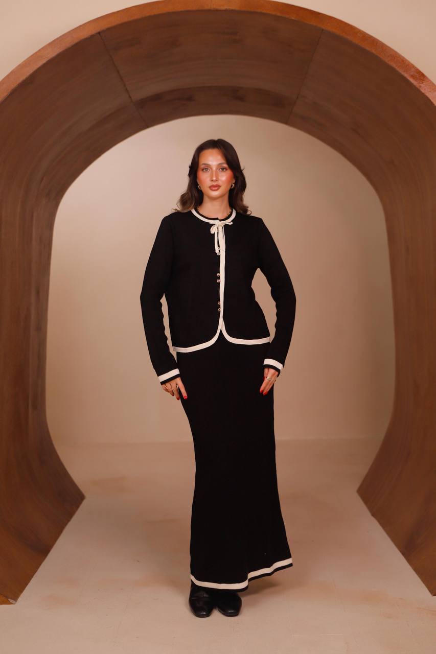 Woman wearing the Belle knit skirt set in black with contrast cream trim, front view