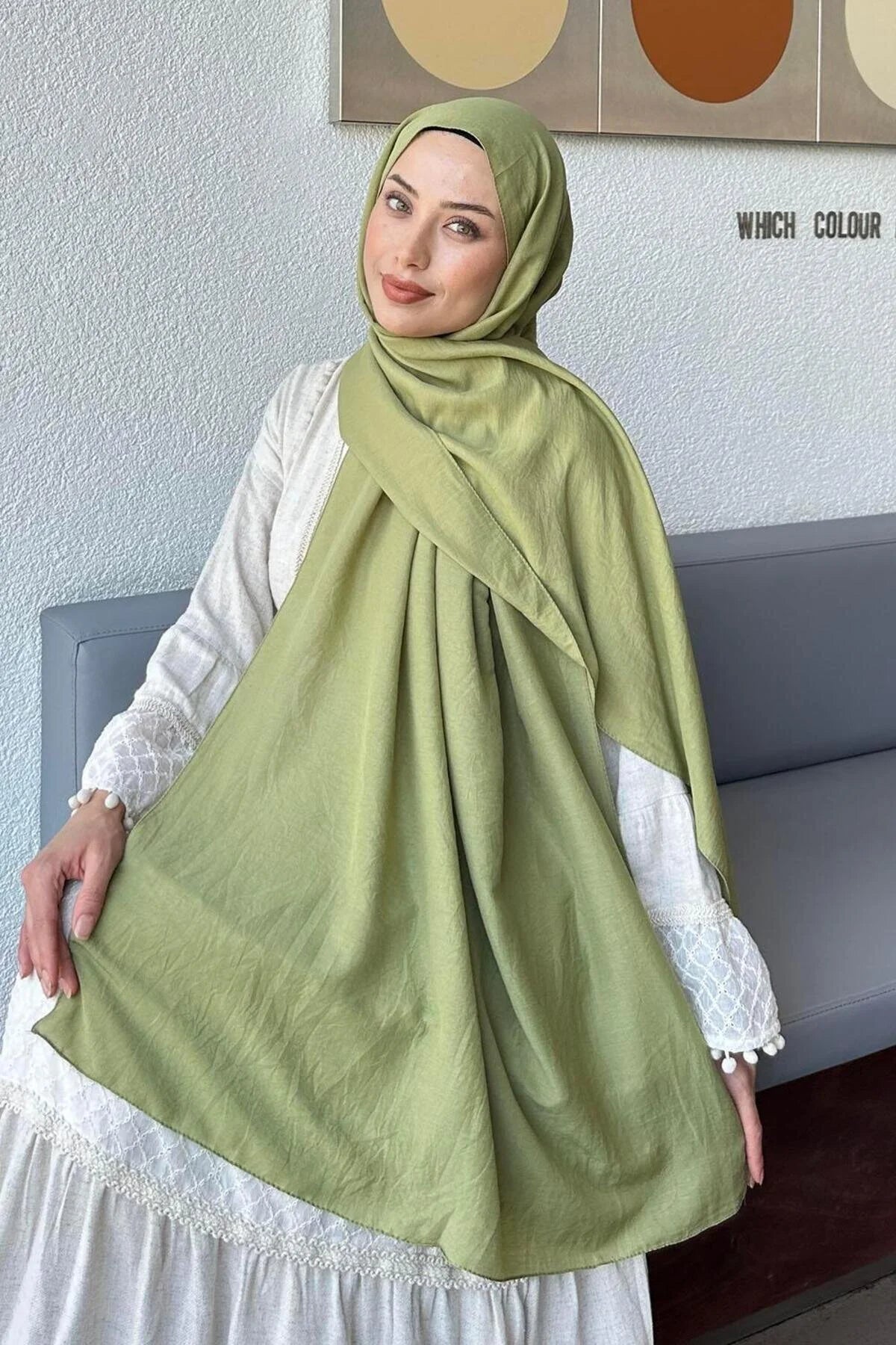 Woman in a pistachio green Comfort Cotton Hijab draped over a white dress, seated view