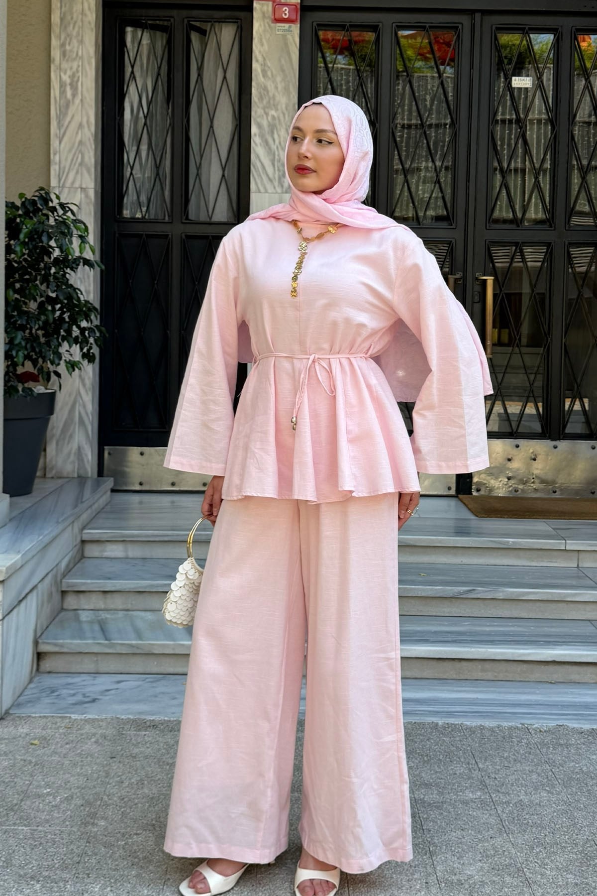 Woman in a hijab wearing the Willow cotton linen set in pink: tie-waist top and relaxed wide-leg pants, front view