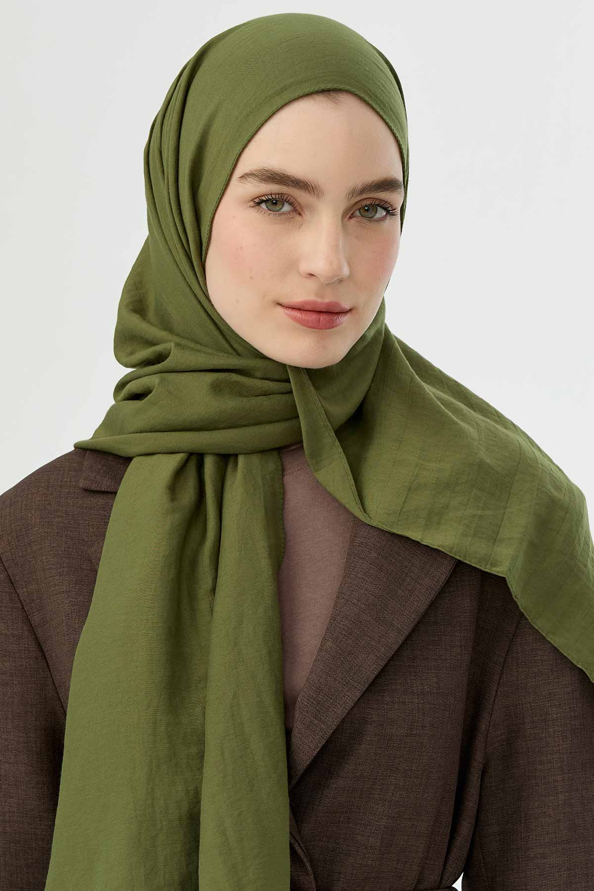 Olive Comfort Cotton Hijab draped softly over a brown coat, front view