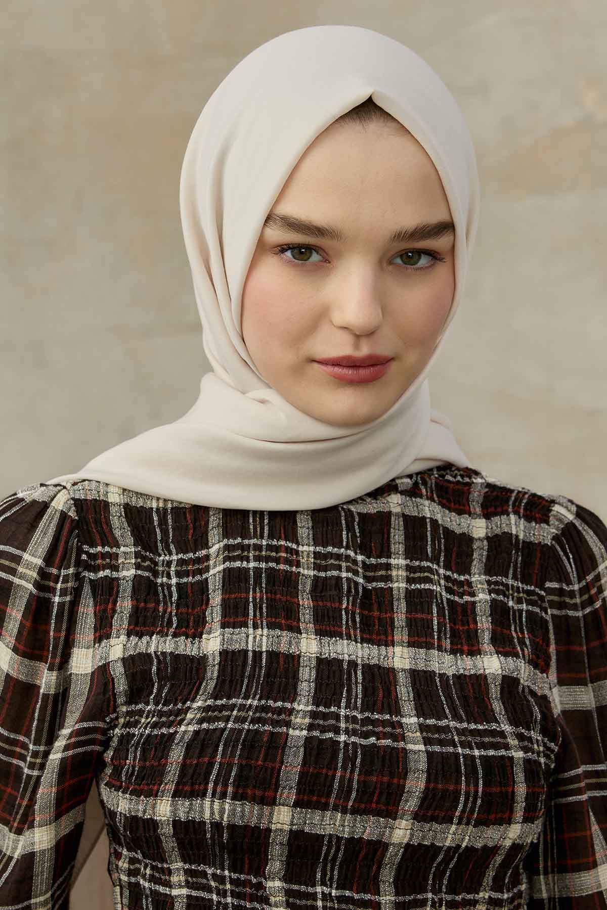Woman wearing the ivory Comfort Cotton Hijab with a brown plaid top, front view