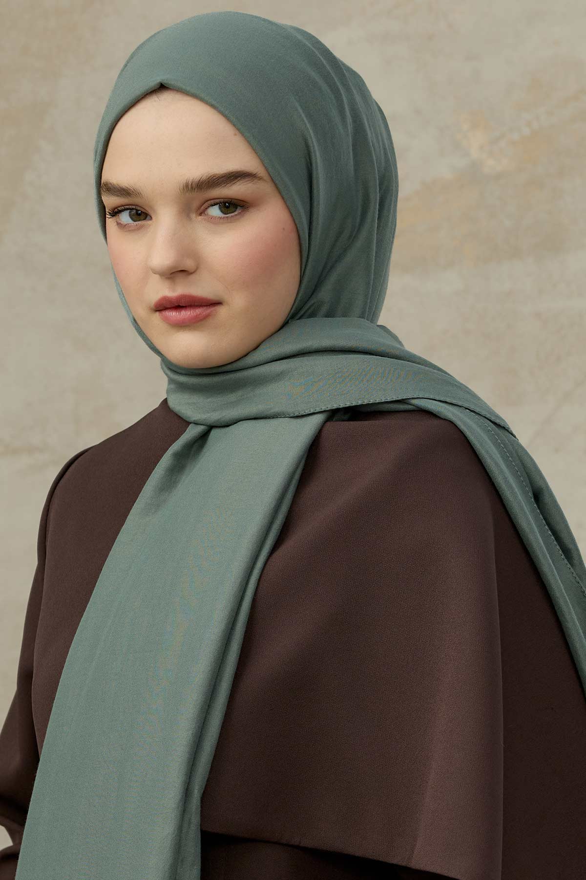 Dusty Teal Comfort Cotton Hijab with a long drape over a brown coat, front view